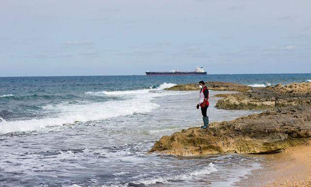 Ein Mann hält an der Libyschen Küste Ausschau nach Leichen, die angespült werden.