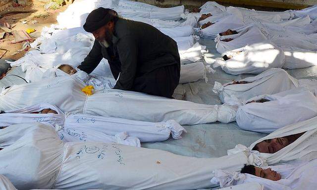 A man holds the body of a dead child among bodies of people activists say were killed by nerve gas in the Ghouta region, in the Duma neighbourhood of Damascus