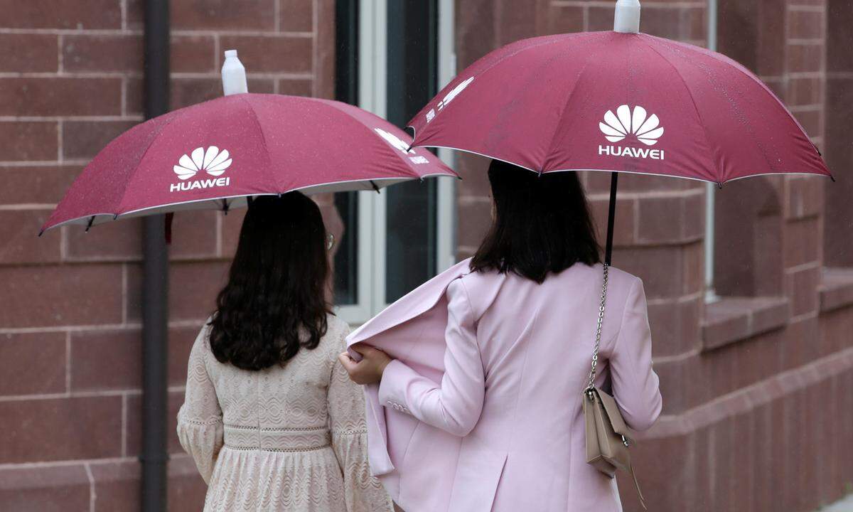 Guests hold umbrellas with Huawei logos in the rain at Songshan Lake New Campus in Dongguan