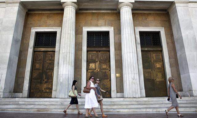 People walk past the headquarters of Bank of Greece in Athens