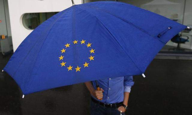 A person with an umbrella featuring the symbol of the European Union walks towards the interim facility of Germany's high constitutional court  in Karlsruhe