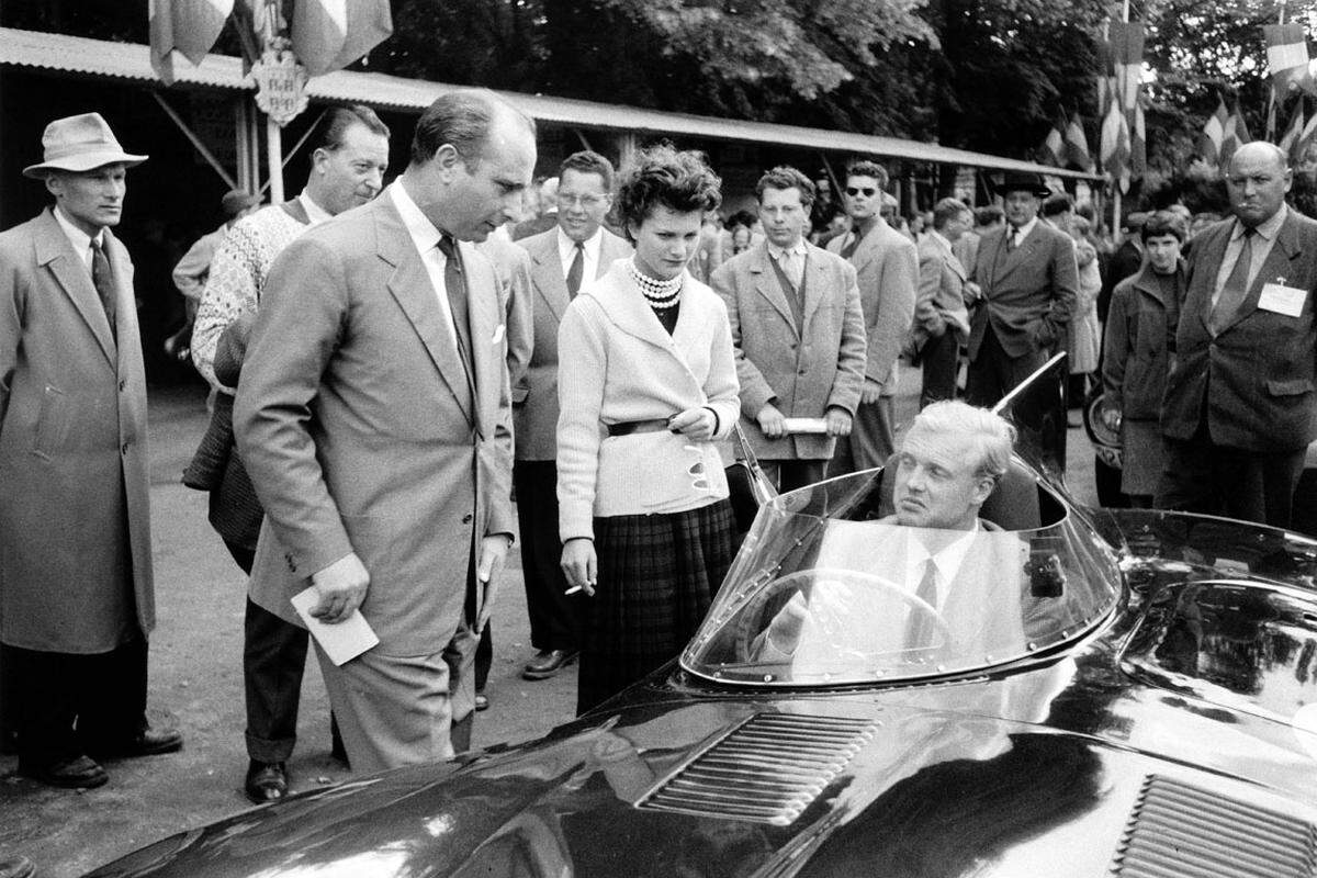 Klar scheint heute, dass die völlig unzureichenden Sicherheitsvorkehrungen und das umstrittene Überholmanöver des Briten Mike Hawthorn (im Auto) Auslöser des Todesdramas waren.Der legendäre Juan Manuel Fangio (links), der die Tragödie aus kurzer Distanz mitansehen muss, kehrte übrigens nie wieder nach Le Mans zurück.