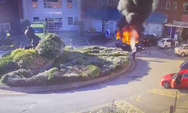 Surveillance camera footage shows a man extinguishing a burning taxi following an explosion, outside Liverpool Women's hospital