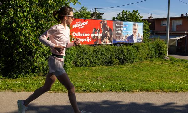 Eine Joggerin läuft an Wahlkampfplakaten in der kroatischen Hauptstadt Zagreb vorbei. 