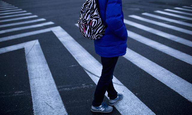 A man carries a backpack in a crosswalk at Lujiazui financial district of Pudong, in Shanghai
