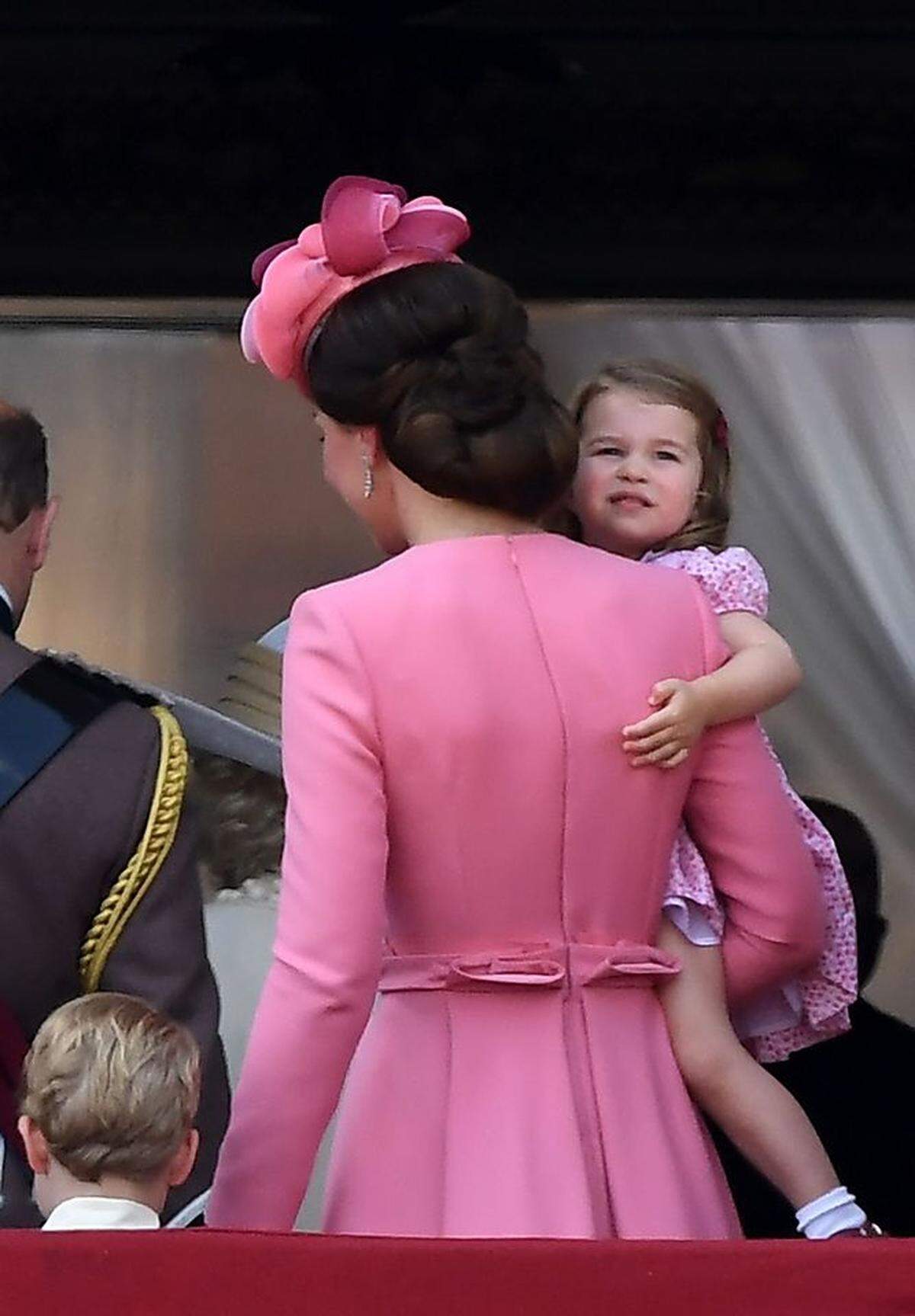 Wir möchten den Auftritt dennoch versöhnlich enden lassen: also noch ein Foto von Kate und ihrem Kleid und der Schneiderkunst, die man bei McQueen offenbar doch ab und an anwendet. (Eigentlich haben wir dieses Foto hauptsächlich wegen Prinzessin Charlotte angehängt: Sie wird immer frecher, und zeigte sich während der Parade wesentlich faszinierter von Flugzeugen als ihr Bruder. Wir hoffen auf eine neue Pilotenkarriere bei den Mountbatten-Windsors.)