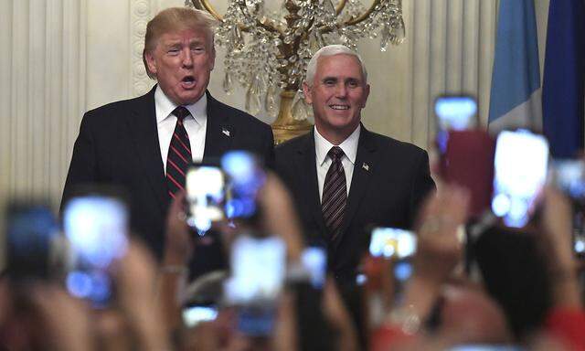 President Donald Trump (L) and Vice President Mike Pence are greeted by guests and their mobile phones as they arrive fo