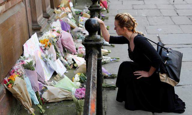 Trauer um die Opfer von Manchester. Eine Frau legt Blumen im Zentrum der britischen Stadt nieder und hält inne.