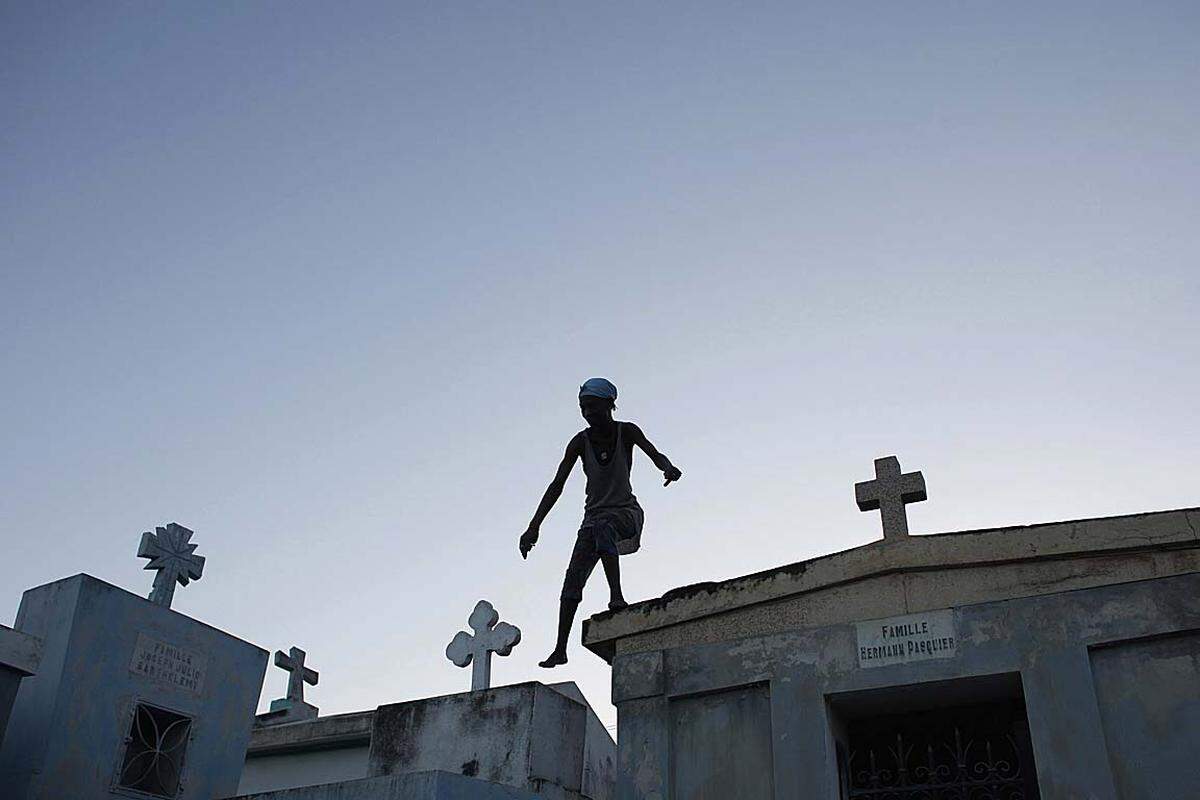 Zu Allerheiligen springt ein Voodoo-Priesterin auf einem Friedhof herum. In Haiti wird das Totengedenken mit Alkohol, Musik und Opfern für Lord Samdi, den Wächter der Toten, gefeiert.