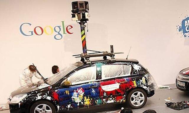 Visitors walk past painted cars with mounted cameras used for Google street view at the CeBIT compute