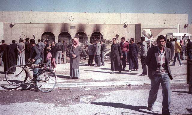 Iraqis walk past the bombed Amaria shelter in Baghdad