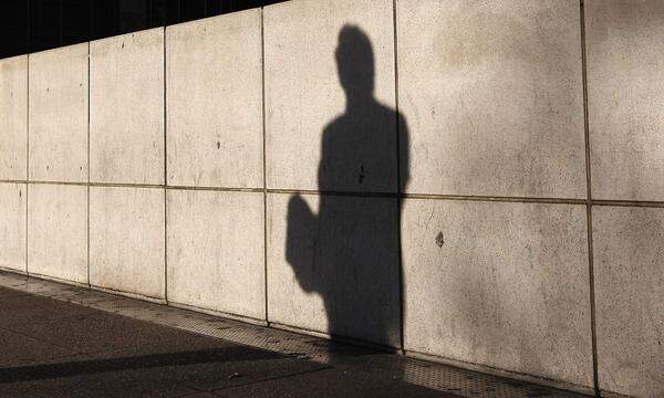 The shadow of a man is cast on a wall at Canary Wharf financial district