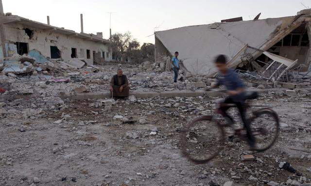 A boy rides a bicycle in a damaged site from what activists said was barrel bombs dropped by forces loyal to Syria´s president Al-Assad in the southern town of Bosra al-Sham, Deraa province