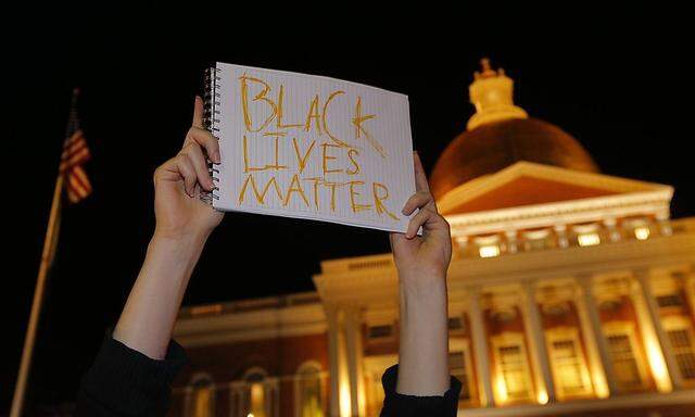 Man holds a sign reading ´Black Lives Matter´ in front of the State House in Boston