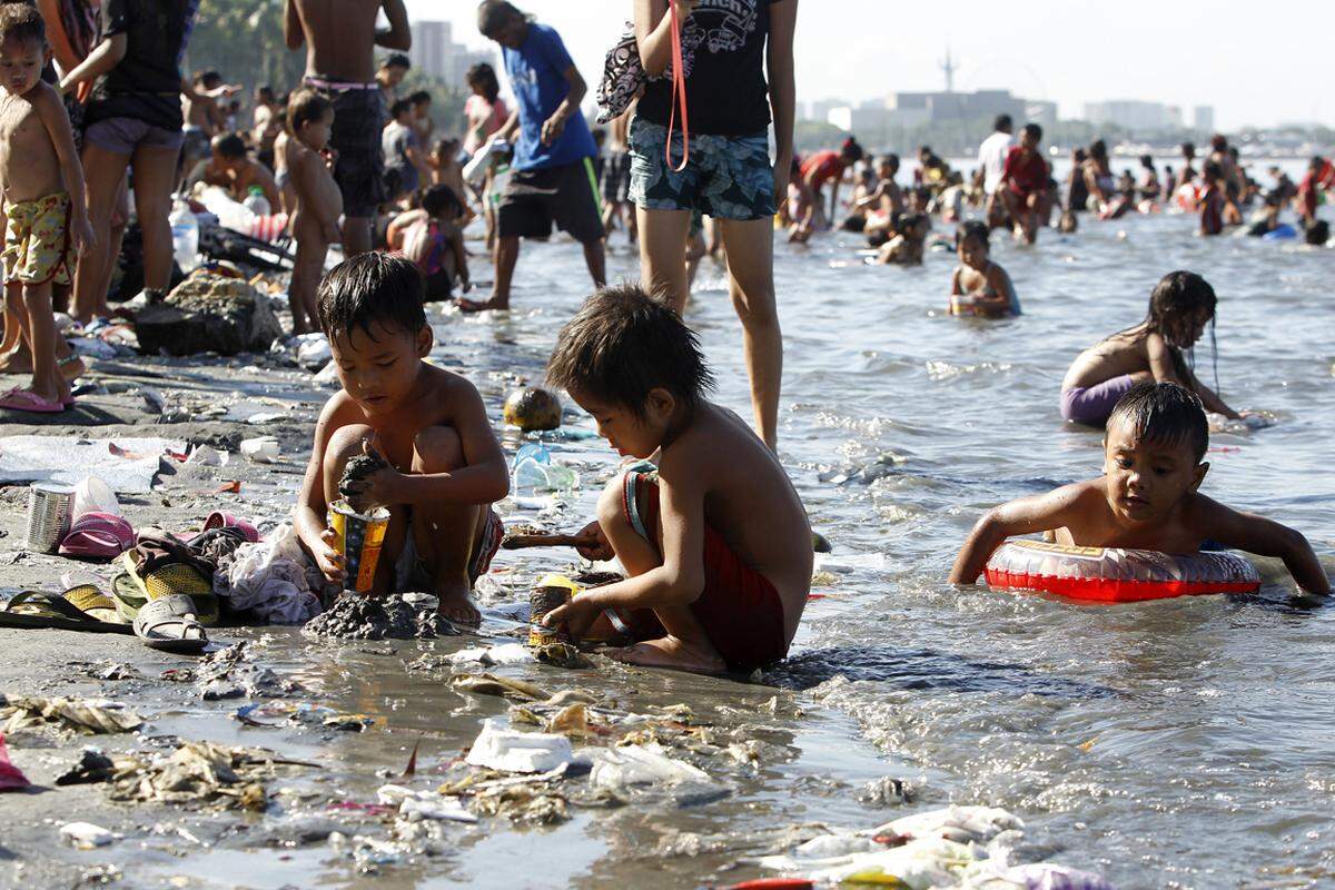 Kinder spielen im völlig verdreckten Sand in der Bucht von Manila (Philippinen) am Ostersonntag 2013. Obwohl die lokalen Behörden vor dem Bad wegen Gesundheitsrisiken warnen, verbringen viele Familien hier ihre Osterfeiertage.