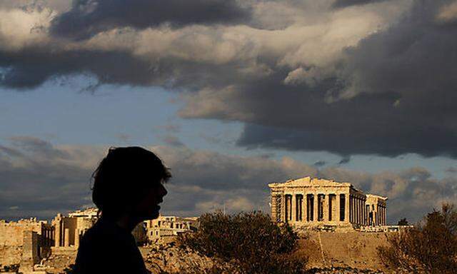 A tourist walks at Filopalous hill as at the background stands the ancient Parthenon temple on the Ac
