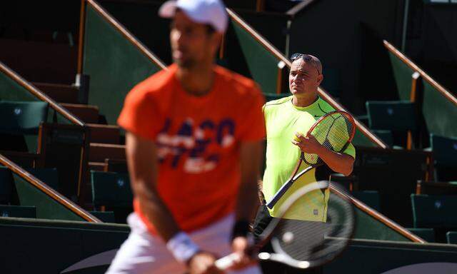 Novak Djoković beim Training in Roland Garros. Andre Agassi beobachtet das Geschehen im Hintergrund.
