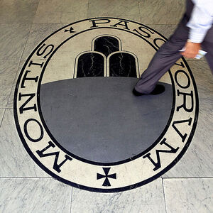 A man walks on a logo of the Monte Dei Paschi Di Siena bank in Rome