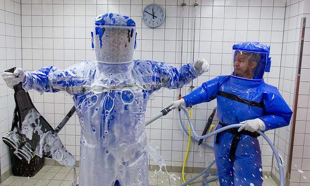 Physicians clean each other in disinfection chamber after cleaning their protective suits at quarantine station for patients with infectious diseases in Berlin