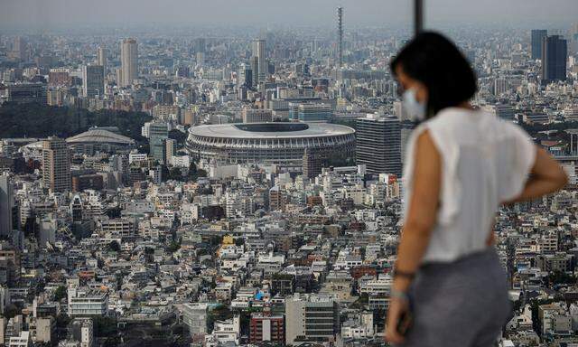 The National Stadium, the main stadium of Tokyo 2020 Olympics and Paralympics, is seen through a visitor wearing a protective face mask amid the coronavirus disease (COVID-19) in Tokyo