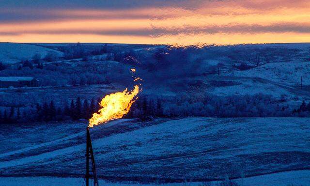 FILE PHOTO: A natural gas flare on an oil well pad burns as the sun sets outside Watford City, North Dakota