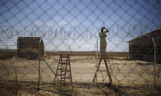 An Israeli worker repairs a fence damaged by a tank in Kibbutz Nahal Oz