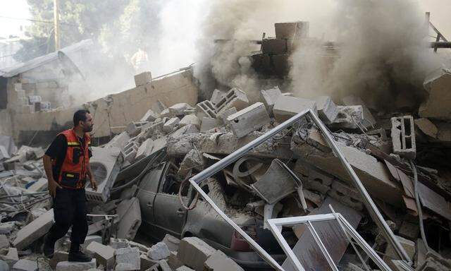 A Palestinian firefighter participates in efforts to put out a fire from the wreckage of a house in Gaza City