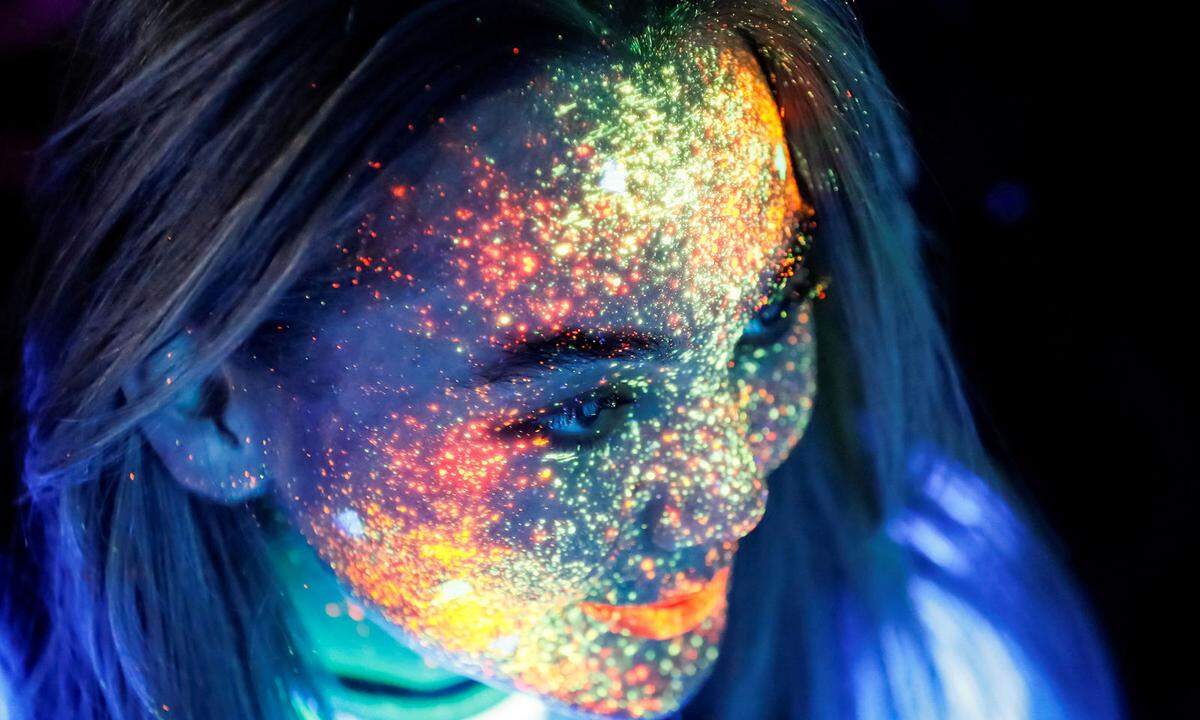 15. September. Wie Sternenstaub auf der Haut: Eine junge Frau in Kasachstan hat ihr Gesicht in fluoriszierende Farbe gehüllt.