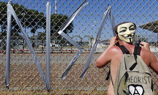 A protester tapes letters on a fence of the 'Dagger Complex' during a demonstration against the NSA in Griesheim