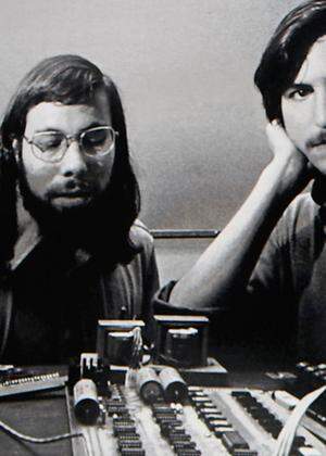 Apple CEO Steve Jobs stands beneath a photograph of him and Apple-co founder Steve Wozniak during the launch of Apple´s new ´iPad´ tablet computing device in San Francisco