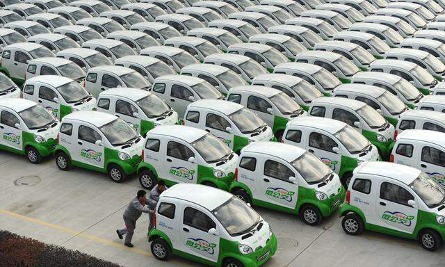 Arbeiter rollen ein E-Auto auf den Parkplatz einer Fabrik im chinesischen Changxing.