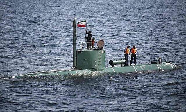 Military personnel place a flag on a submarine during the Velayat-90 war games by the Iranian navy in