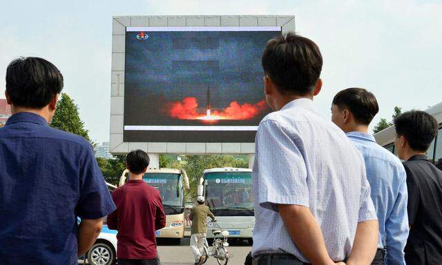Bürger von Pjöngjang bewundern den Raketentest auf einer Riesenleinwand.  