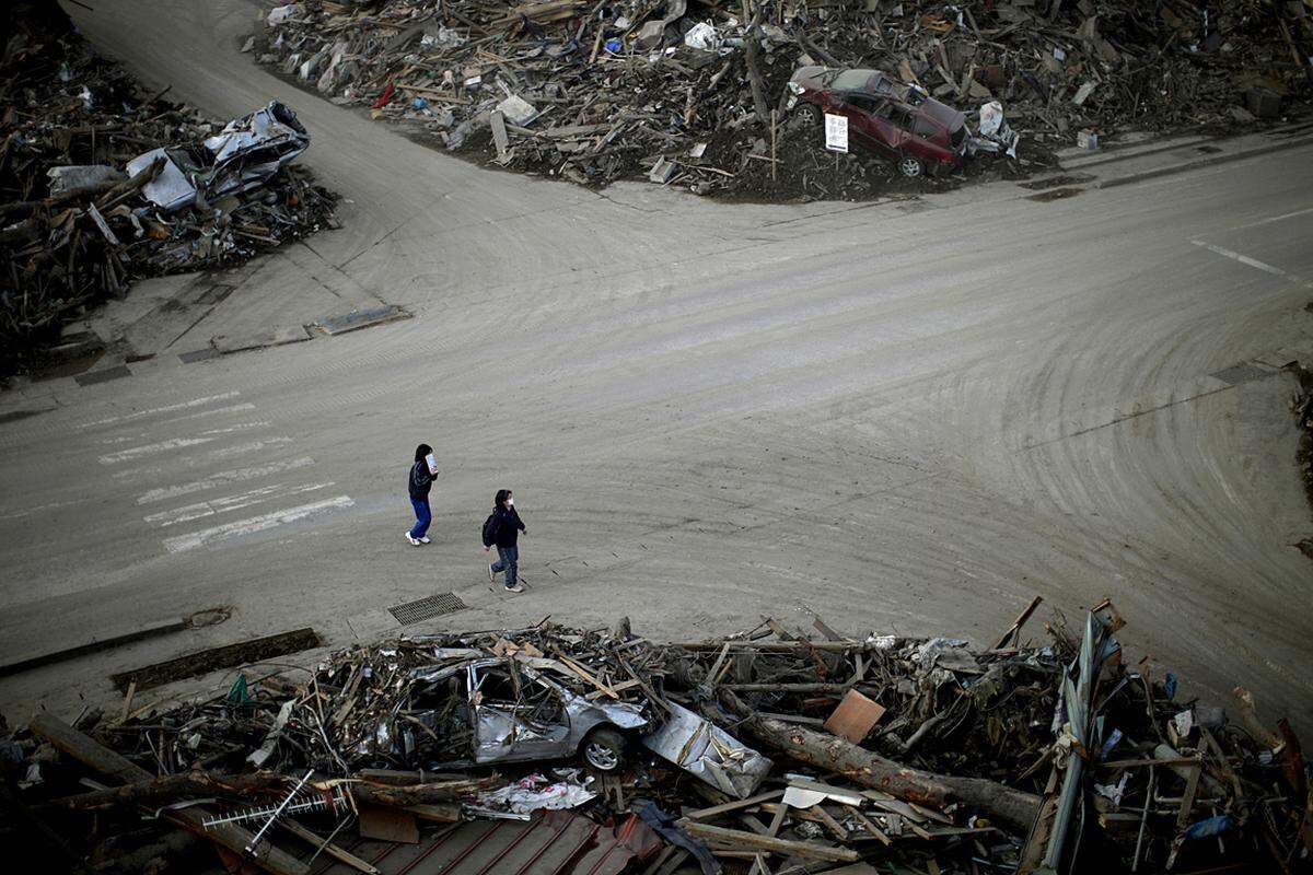 Zwei Anrainer spazieren durch ihre völlig demolierte Siedlung in Taro.