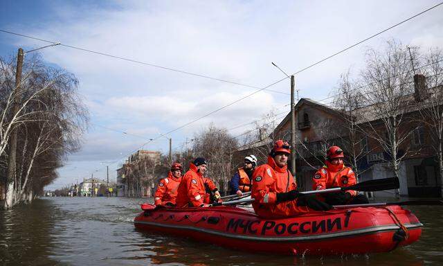 Rettungskräfte fahren in einem Schlauchboot auf einer überfluteten Straße, nach dem Dammbruch bei Orsk in der russischen Region Orenburg.