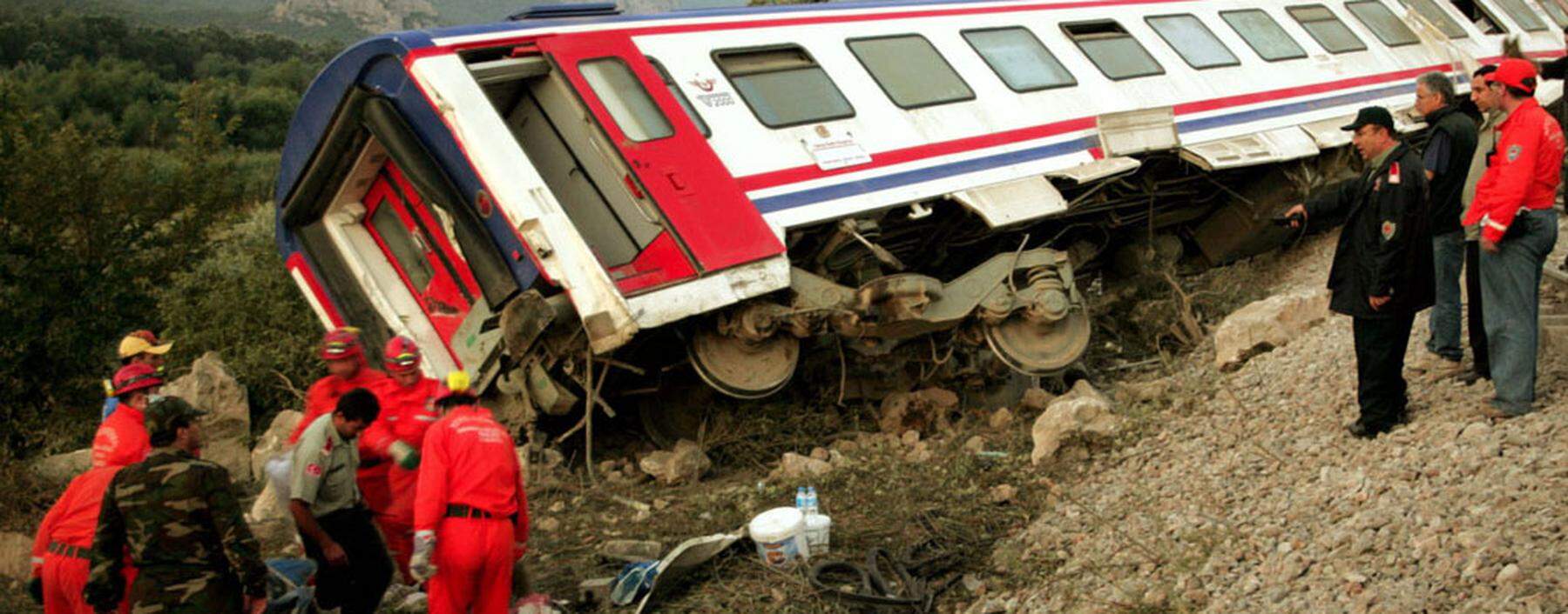 Rescue workers stand near a wagon of a derailed Turkish express train early July 23, 2004, near Pamu..