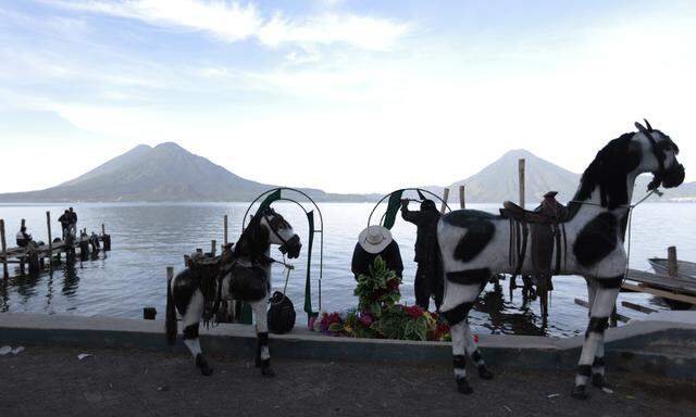 Men stand next to dummy horses in Atitlan, in the Solola region, early morning