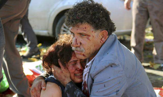 An injured man hugs an injured woman after an explosion during a peace march in Ankara