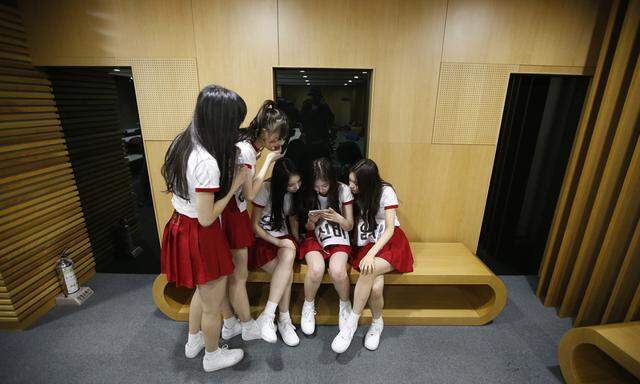 Members of South Korean girl group GFriend watch a recording of their stage performance during a dress rehearsal for The Show in Seoul