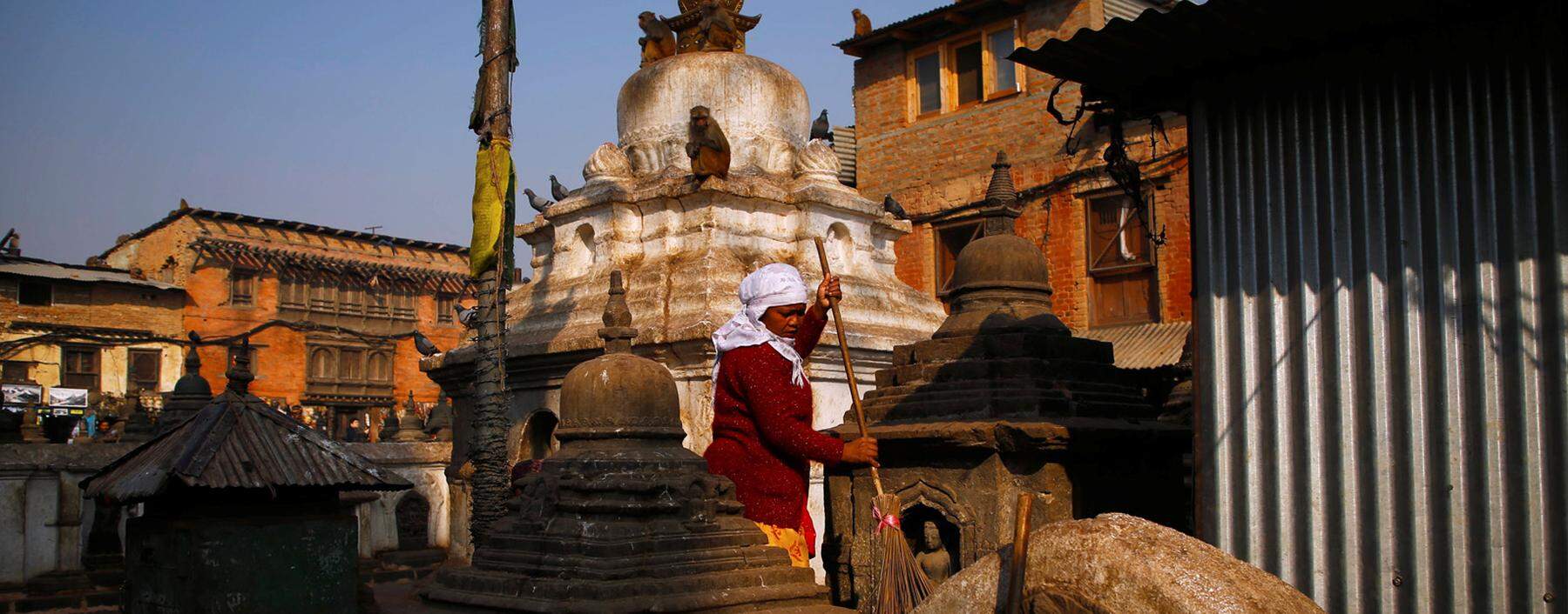 A woman sweeps at the premises of Swayambhunath Stupa in Kathmandu