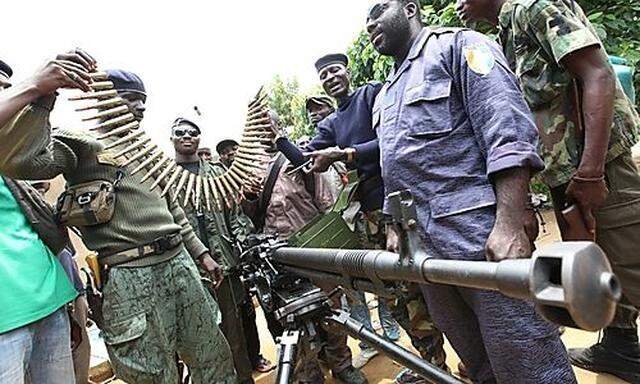 Pro-Ouattara fighters hold ammunition and weapons they say were taken from Ivorian government forces,