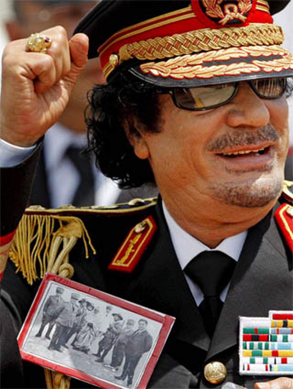 Der findige Diktator benutzt seine Kleidung auch schon einmal als politisches Statement: Auf seine fantasieartig wirkende Uniform pinnte er sich bei einem Italien-Besuch ein Bild des Helden des anti-italienischen Widerstands in Libyen.