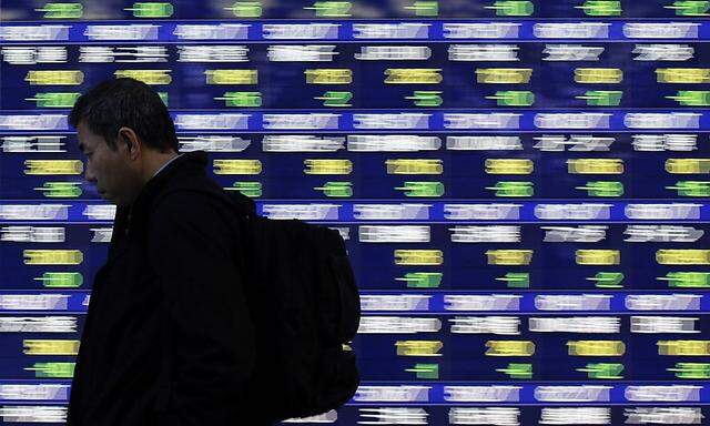 A man walks past at an electronic stock quotation board board outside a brokerage in Tokyo
