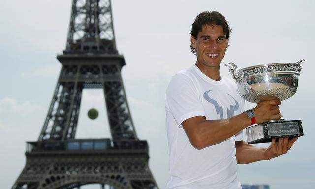 Nadal of Spain poses with his trophy for photographers near the Eiffel Tower in Paris