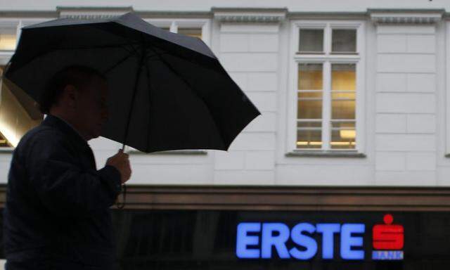 A man with an umbrella passes the entrance of the headquarters of Austrian Erste Group Bank  in Vienna