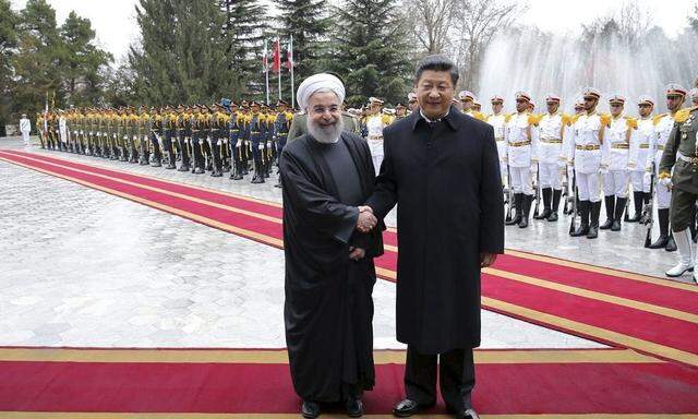 Iranian President Hassan Rouhani shakes hands with Chinese President Xi Jinping during a welcoming ceremony in Tehran