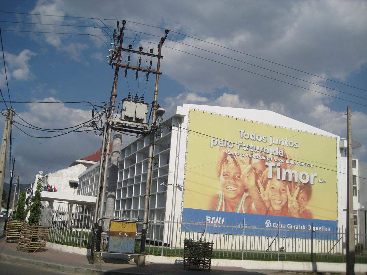 Timor-Leste wird auch Osttimor genannt, aber das Land legt Wert auf die portugiesische Ursprungsbezeichnung. Timor-Leste ist schließlich einer der jüngsten Staaten der Welt, 2002 als 191. Mitglied der Vereinten Nationen anerkannt, da will man einen einheitlichen Namen. Außerdem möchte man keine indonesische Provinz mehr sein, das war man lange genug, 1976-2002 als Provinz Timor Timur, was beides “Osten” bedeutet und auf die Außenlage hinweist. Das Plakat in einem Vorort von Dili sagt: “Alle zusammen für die Zukunft von Timor.” Auf Portugiesisch und Bahasa Indonesia. Und ganz ohne Leste.