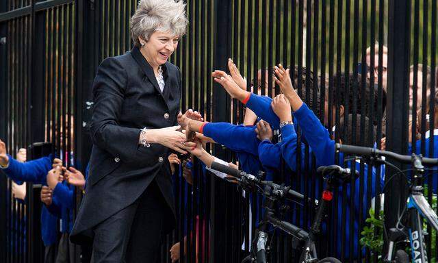 Die britische Regierungschefin Theresa May schüttelt Kindern die Hand. Parteiintern wollen nicht alle ihr die Hand reichen.