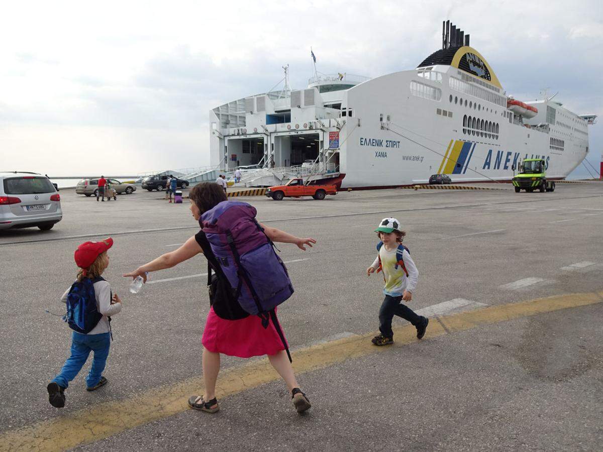 Die Familie besteigt die Fähre der kretischen Reederei ANEK in Patras, Griechenland. Was heißt da, besteigt? Zentrifugale Kräfte zerren sie auseinander.