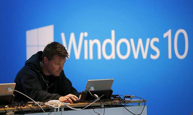 A man works on a laptop computer near a Windows 10 display at Microsoft Build in San Francisco